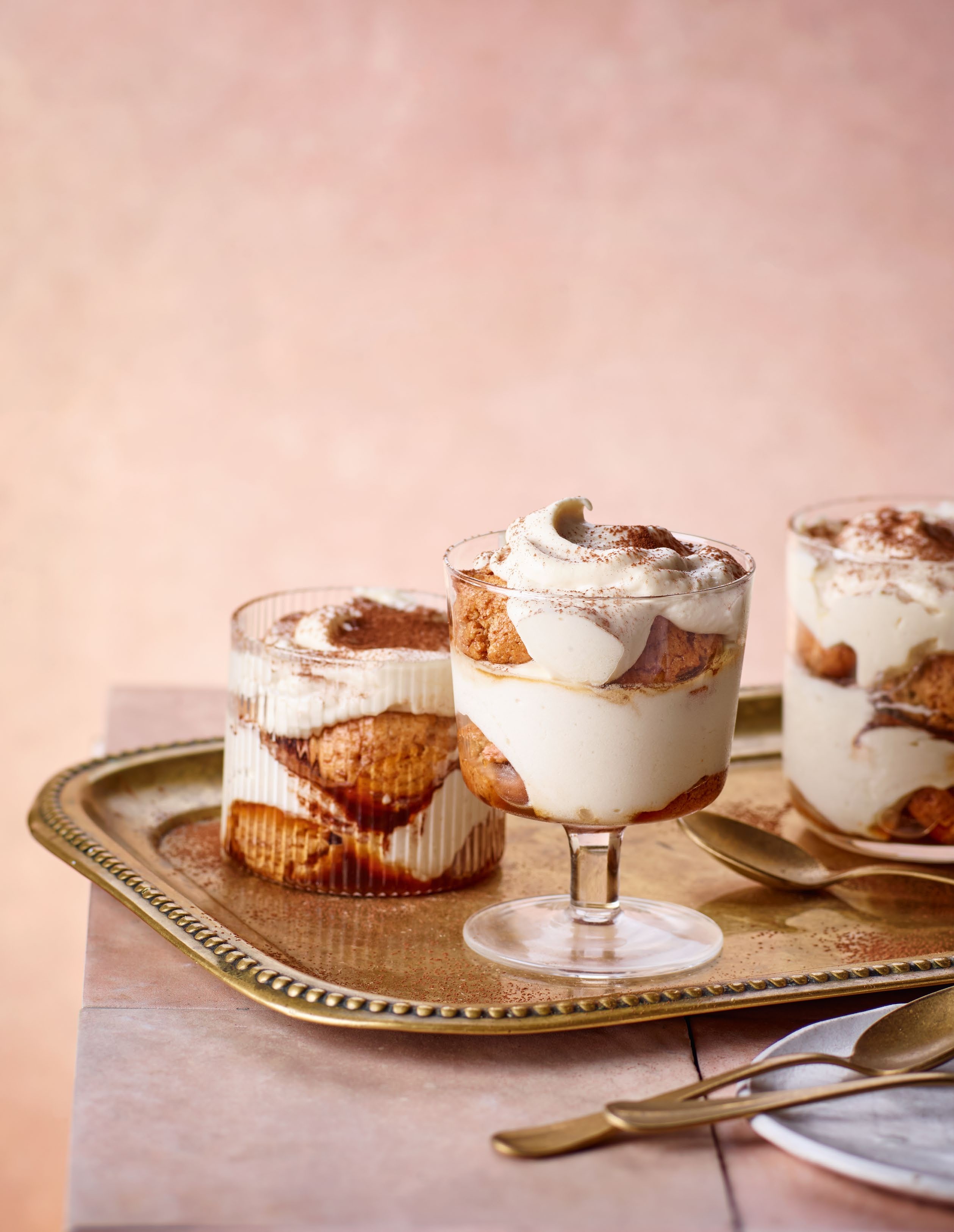 Three elegant servings of a nutty twist on the Italian classic dessert, featuring layers of Frangelico cream and crunchy almond biscuits, displayed on a decorative tray.