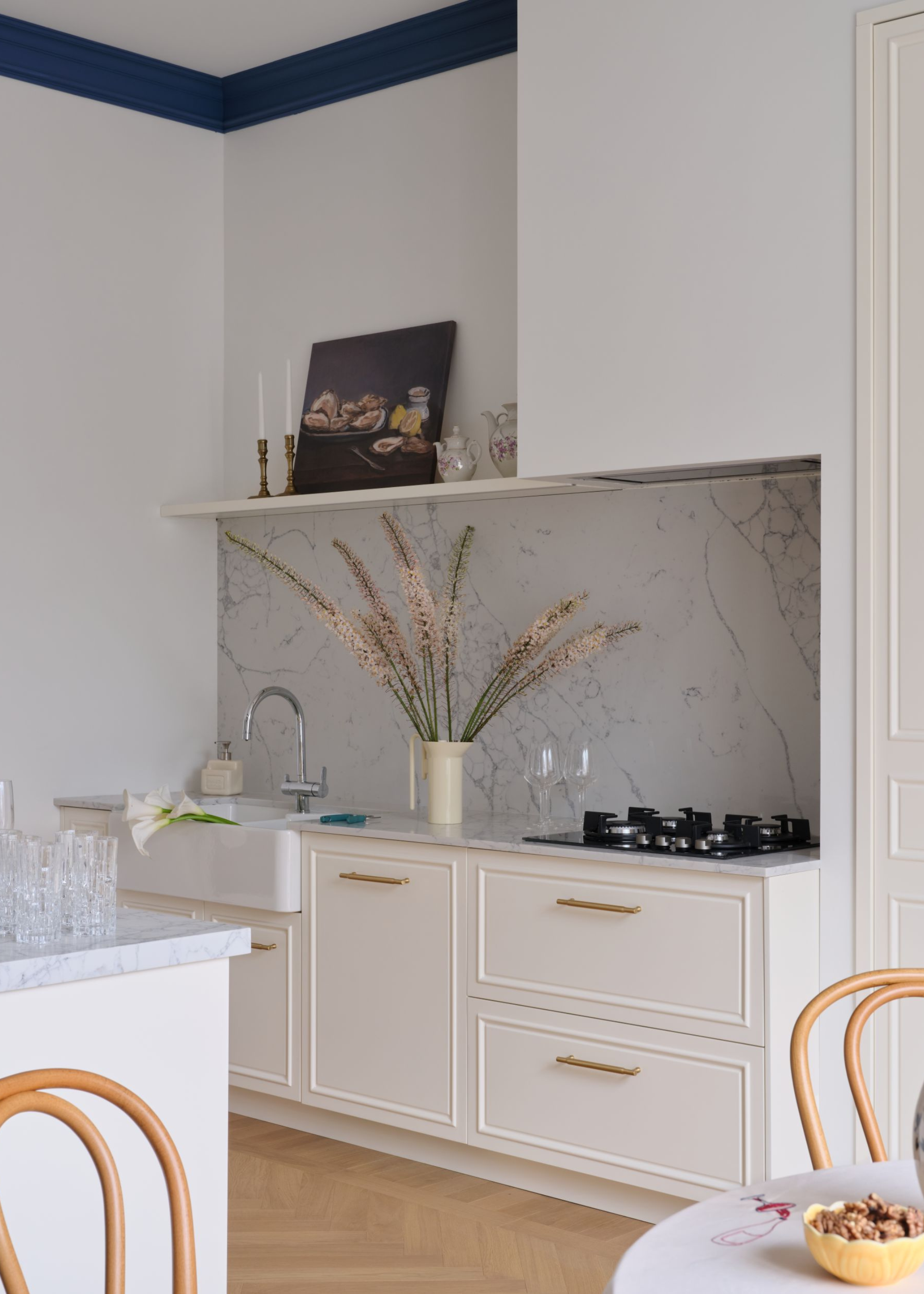 A small kitchen with white cabinetry and a marble splash back with a small hob on the surface