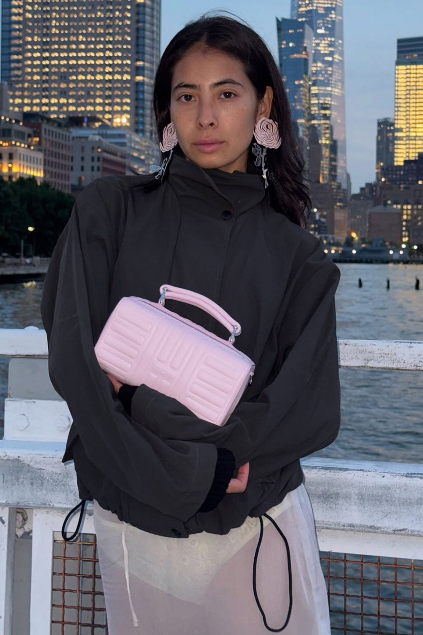 a woman wearing a black jacket and pink clutch bag