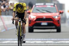 Simon Yates crosses the line at Sestriere with his head bowed in disbelief