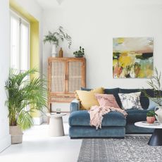 White painted living room with a blue sofa and colourful cushions on it