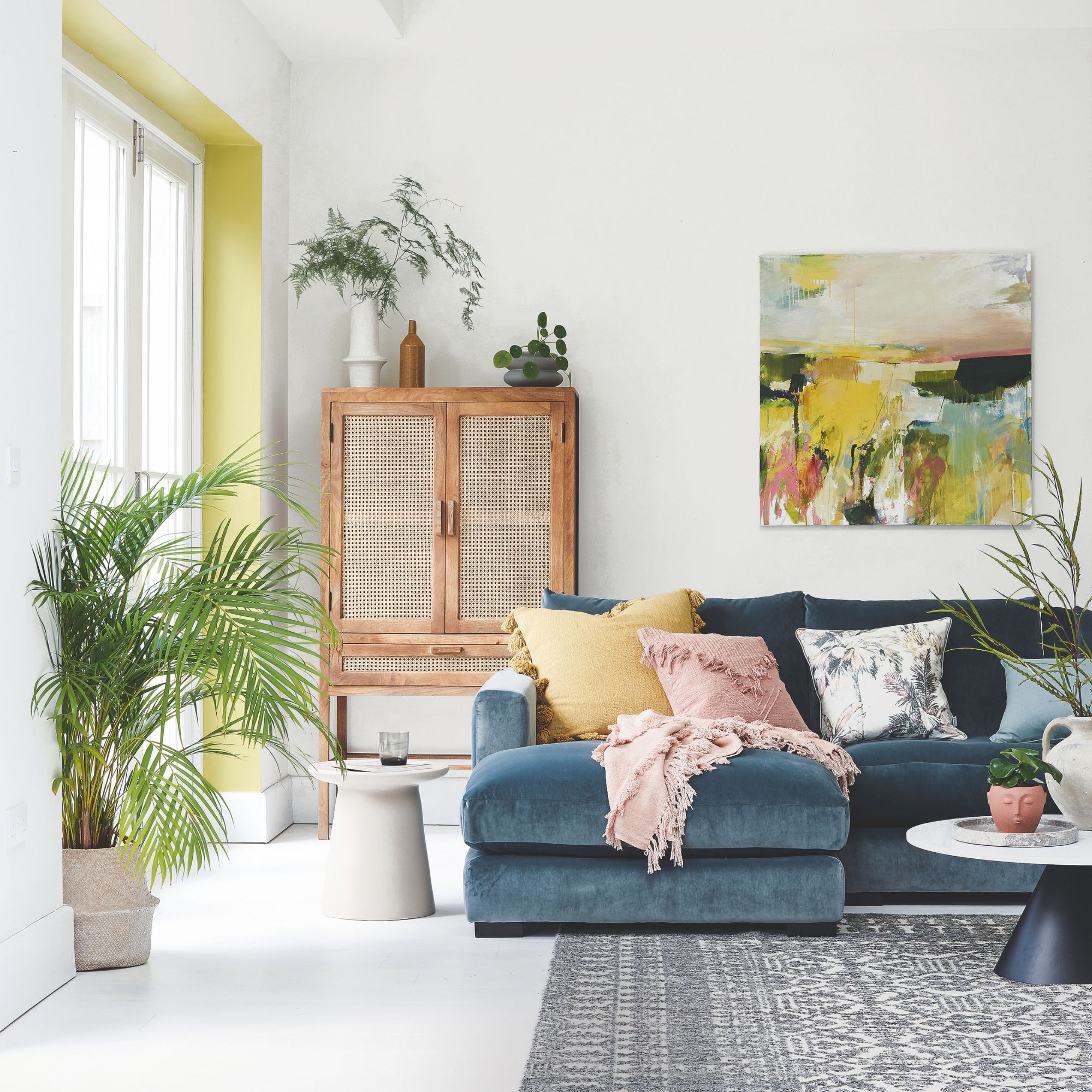 White painted living room with a blue sofa and colourful cushions on it