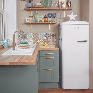 Small kitchen with teal cabinets and a white fridge.