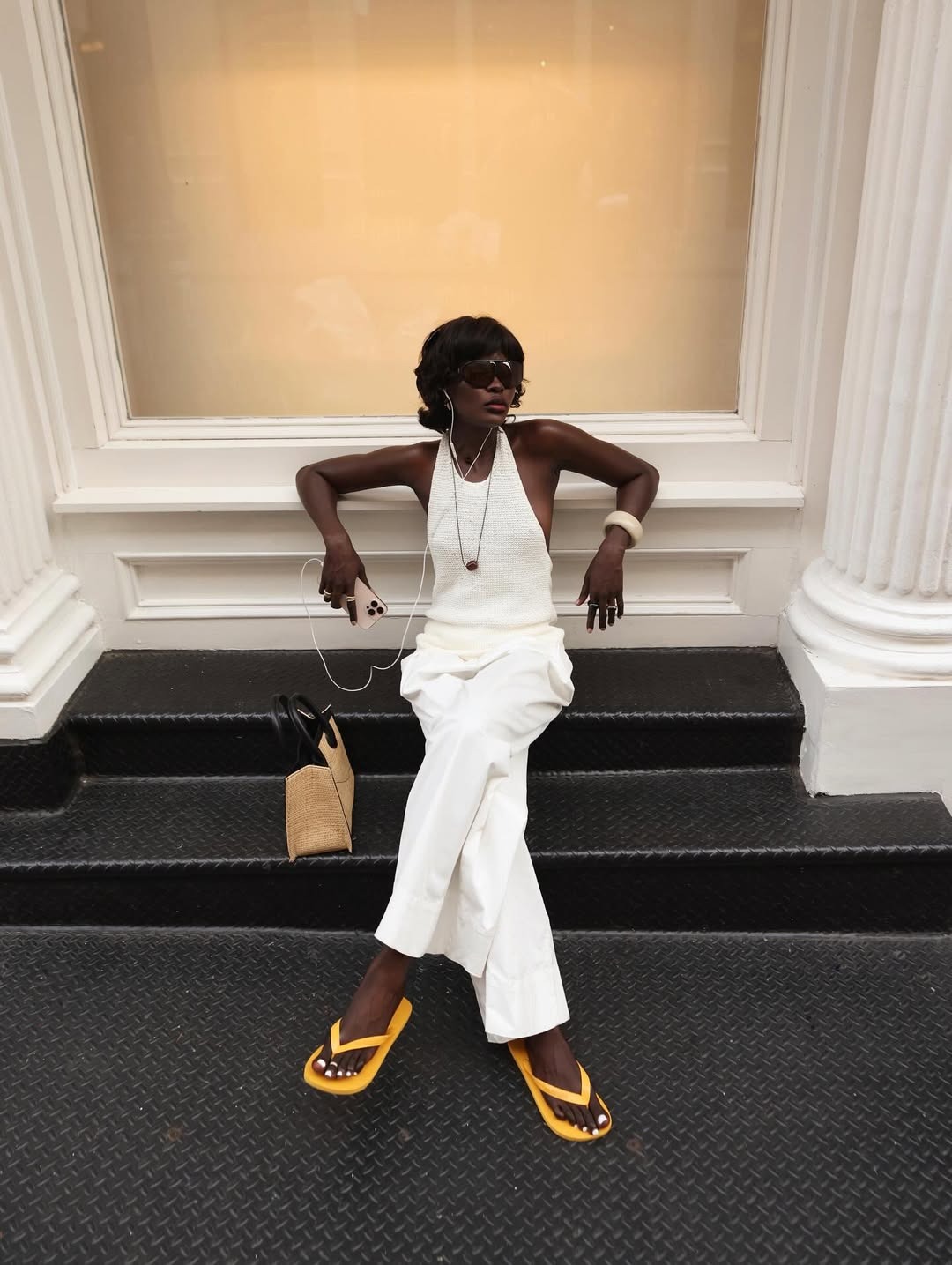 Woman wears white pants with a white halter and yellow flip flops.