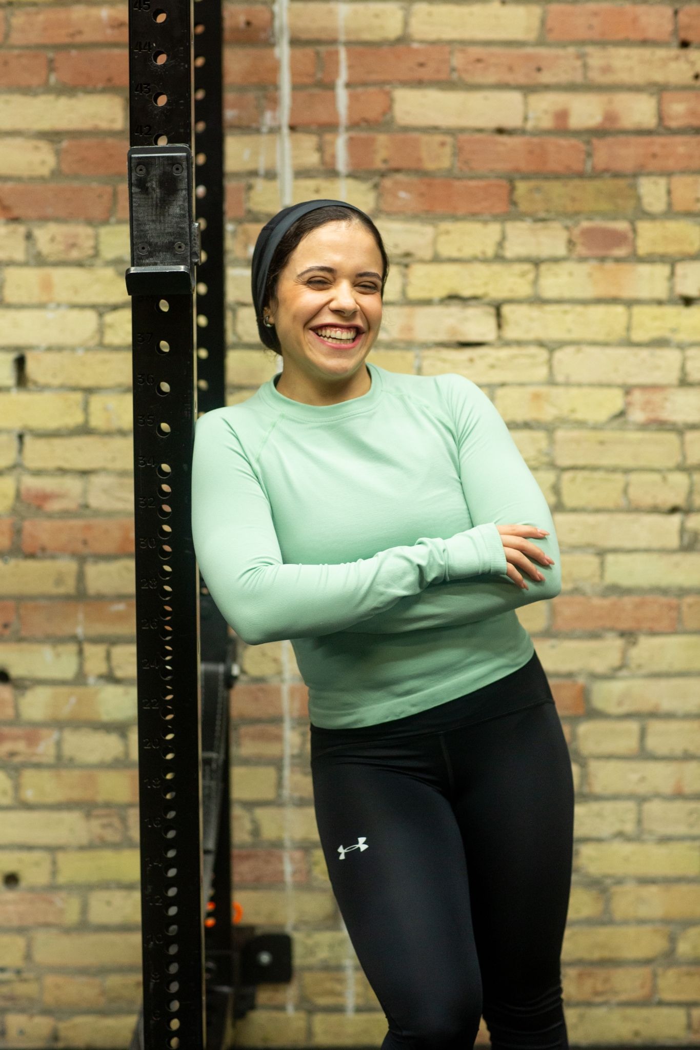 woman smiling at the camera wearing a mint sleeved top and black leggings