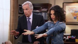 Henry Winkler standing behind Jenny Slate who is holding out her arms on Parks and Recreation.