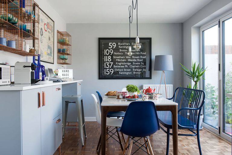 modern dining room with blue chairs, copper open shelving, a floor lamp and exposed bulb pendant lights