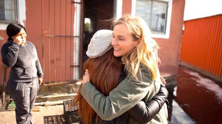 Diane Kruger smiles as she hugs another woman.