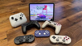 8BitDo controllers on a wooden floor with an iPad playing games
