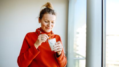 Woman eating yoghurt with a spoon from a glass