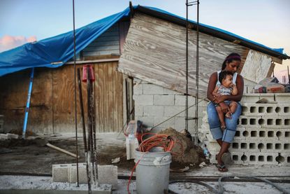 A mother and her child in front of their makeshift home, following Hurricane Maria.
