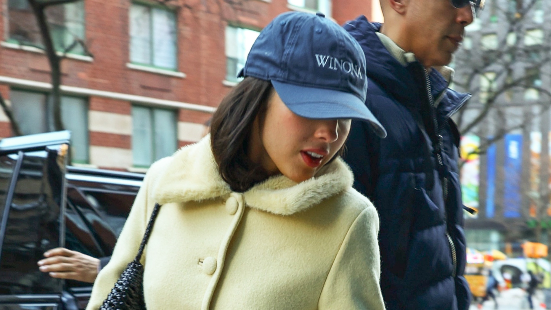 Olivia Rodrigo wearing a baseball cap, yellow coat, bootcut jeans, and ballet pumps in NYC
