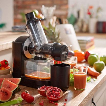 Philips Viva Slow Juicer on a wooden kitchen worktop surrounded by chopped fruit