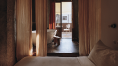 A bedroom with curtains separating the sleeping space from the bathtub