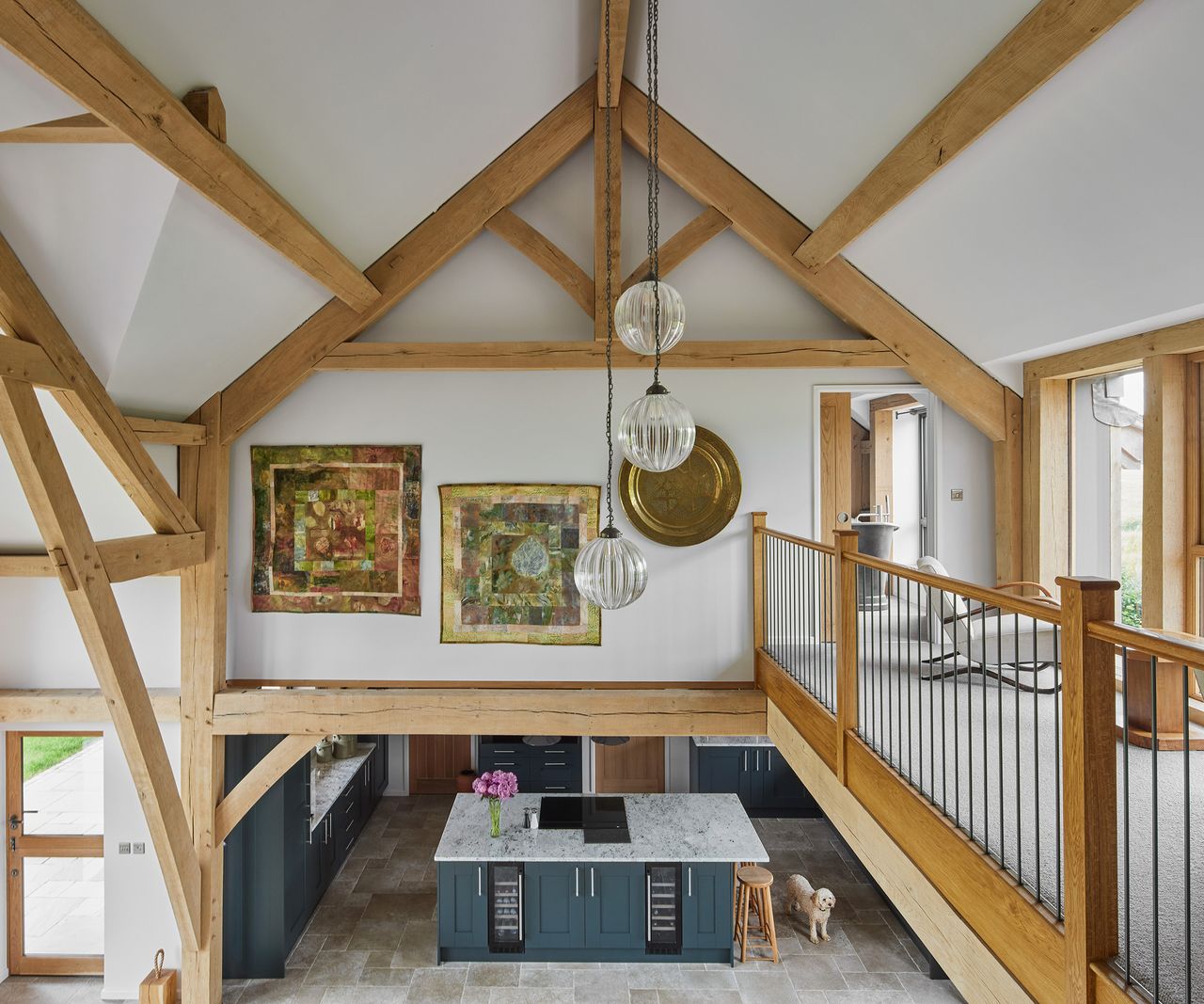 A pitched roof with exposed oak beams in a double-height void looking down into an open plan living space