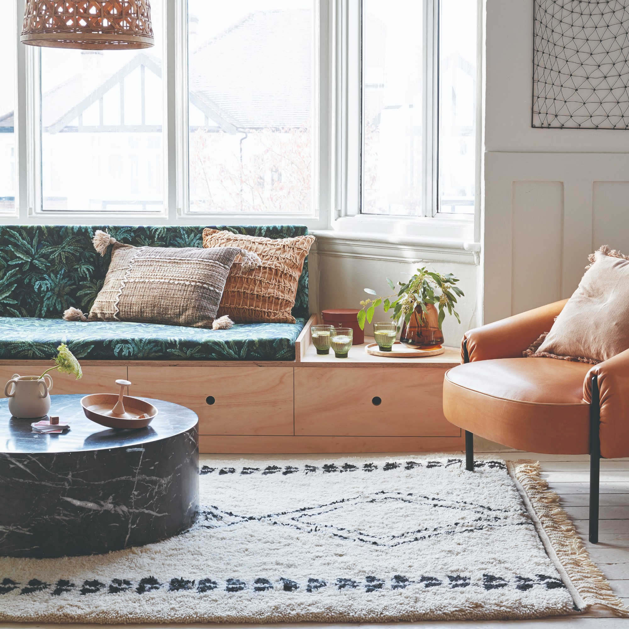 A living room with a light-wood window seat used as a sofa with built-in storage