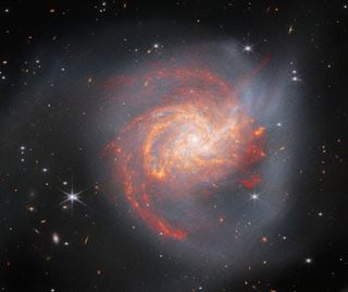 A fiery orange spiral galaxy swirls