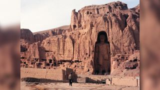 An Afghan walks near the world’s tallest standing statue of Buddha in Bamiyan province in Afghanistan on Dec. 7, 1997, years before the statue was destroyed by the Taliban in 2002.