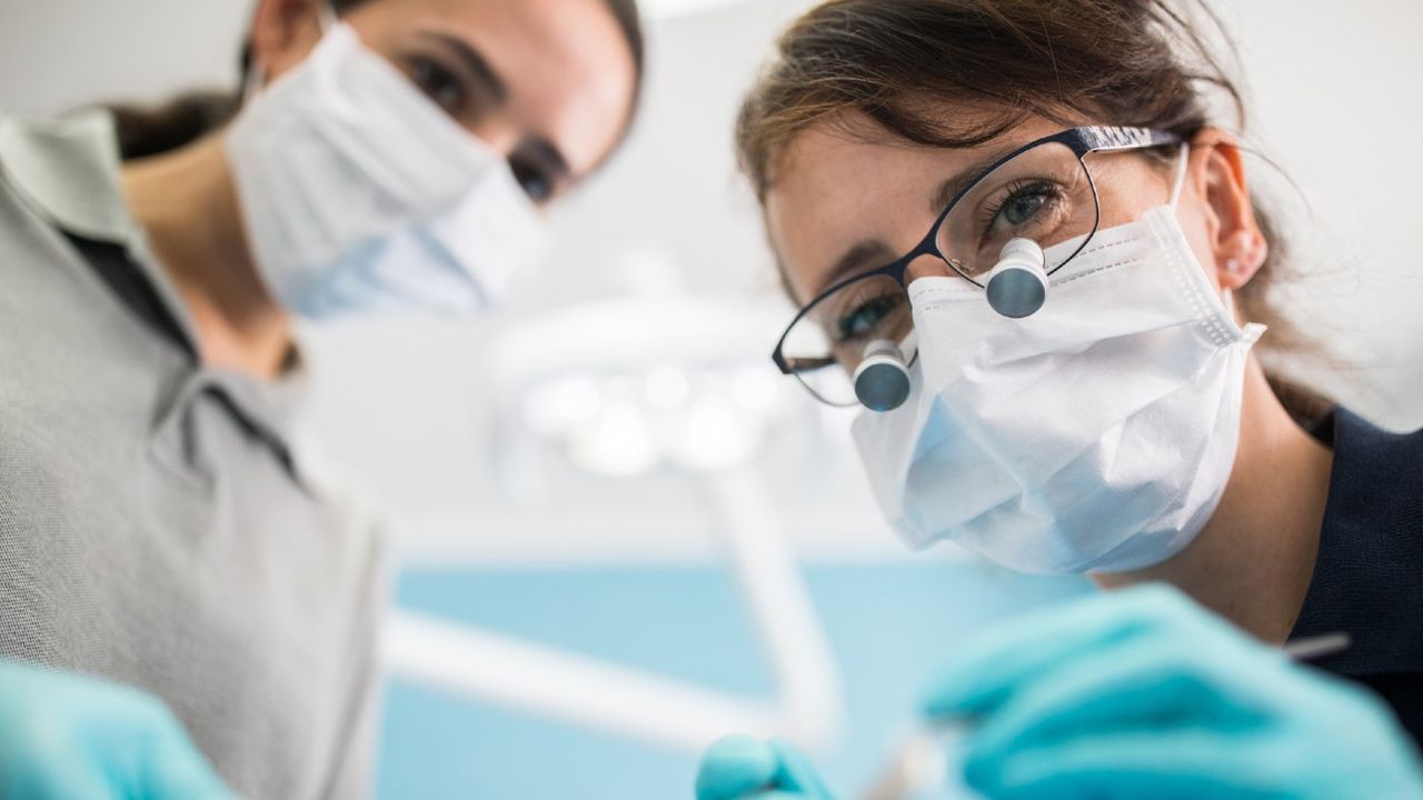 Female dentist examining patient with dental equipment