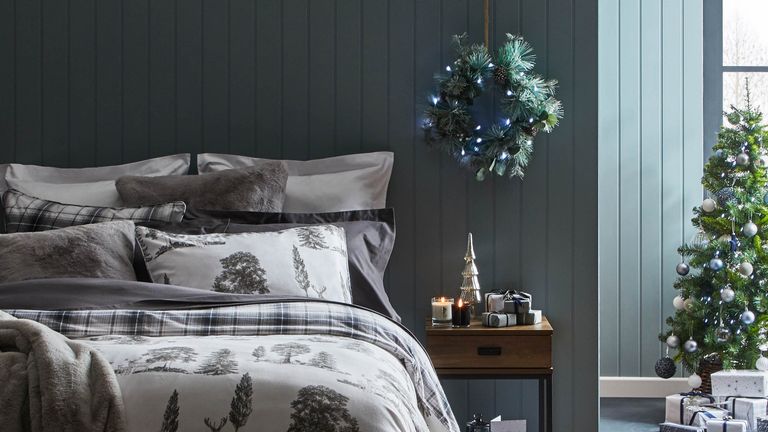 Grey printed bedding on a bed in a grey bedroom with wall panelling christmas decor by by the bedside 