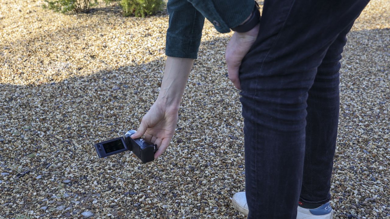 The Sony HDR-CX405 camcorder being held at a low filming angle by a man