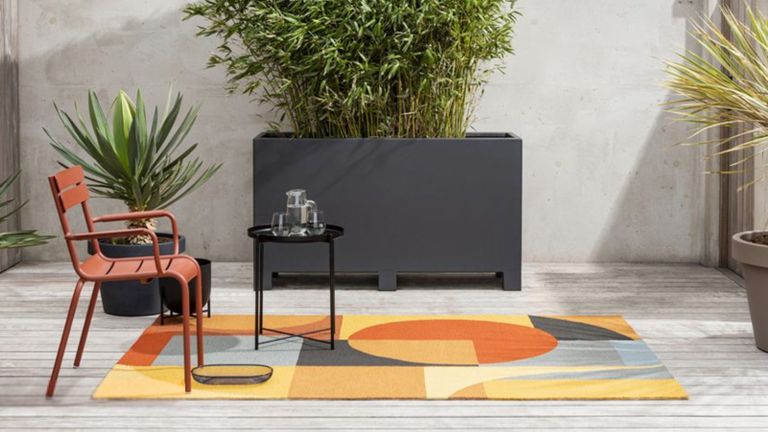 A colourful outdoor rug in a contemporary decked garden