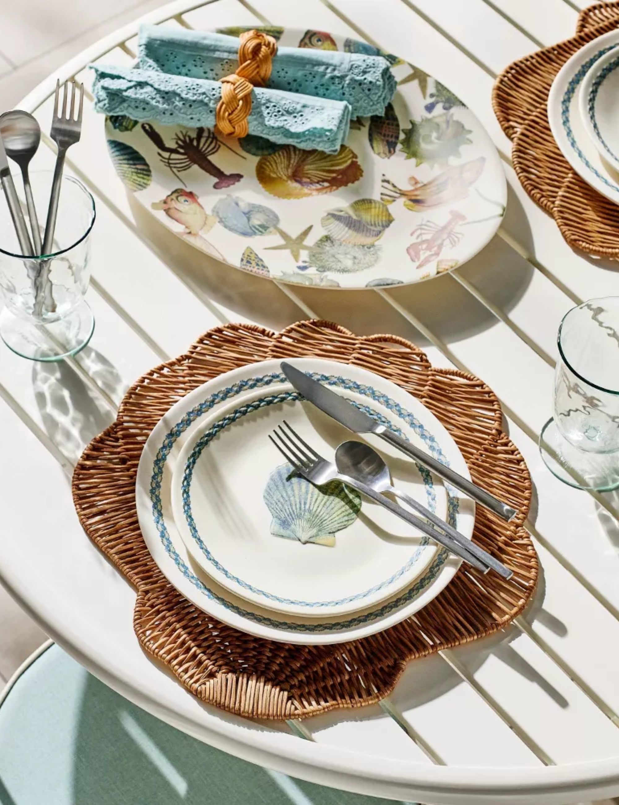 White outdoor patio table styled with shell-motif tableware
