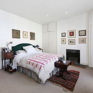 bedroom with white wall and carpet flooring with cushions on bed