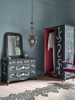 Blue bedroom with upcycled black wardrobe and drawers with a stencilled design