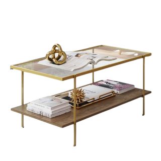 A gold coffee table with two layers, with books and decor on it