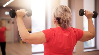 Woman holding dumbbell in each arm at shoulder height