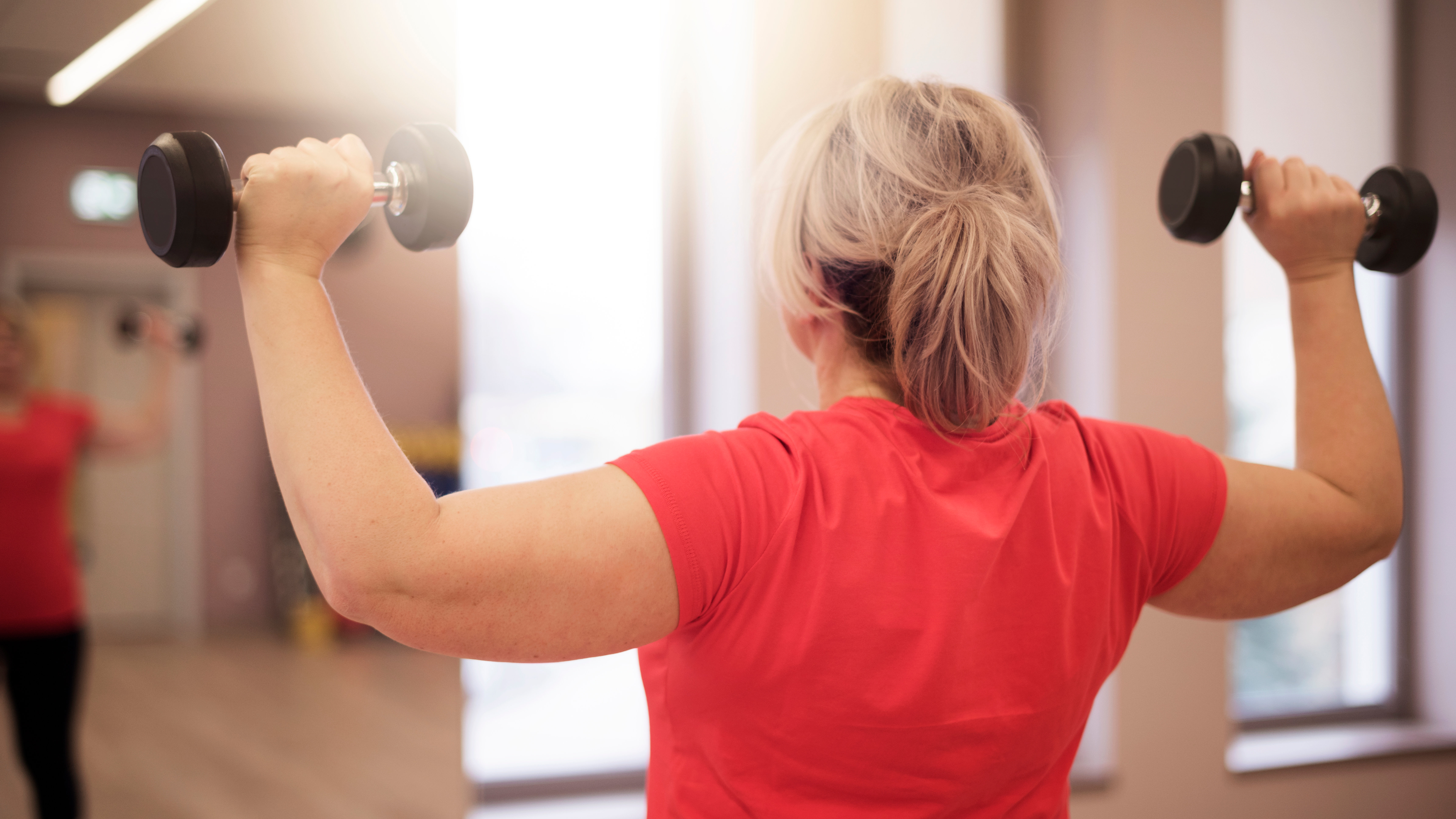 Woman holding dumbbell in each arm at shoulder height