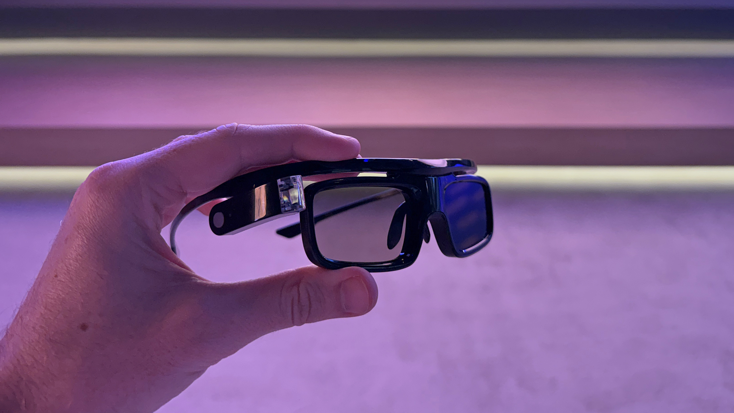 A pair of 3D glasses held in a man's hand