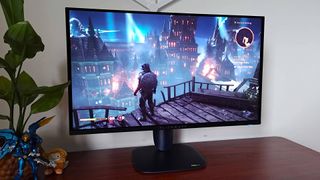 Alienware AW2725Q with Dragon Age: The Veilguard gameplay on screen with player character looking over balcony at city with explosion around buildings.