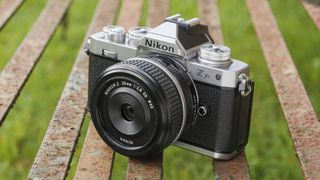 En svart och silvrig Nikon Z fc ligger utomhus på en metallbänk.