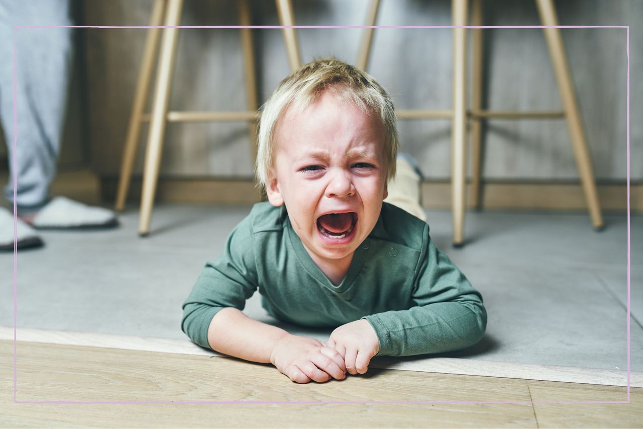 A blonde boy lying on the floor and crying hysterically