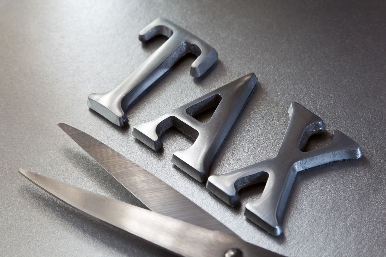 silver tax letters with a silver pair of scissors on a silver background