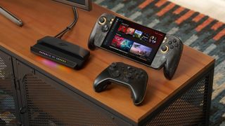 ROG Xbox Ally X20 handheld sitting upright on a desk setup alongside a black wireless controller and an RGB-lit Republic of Gamers dock station.