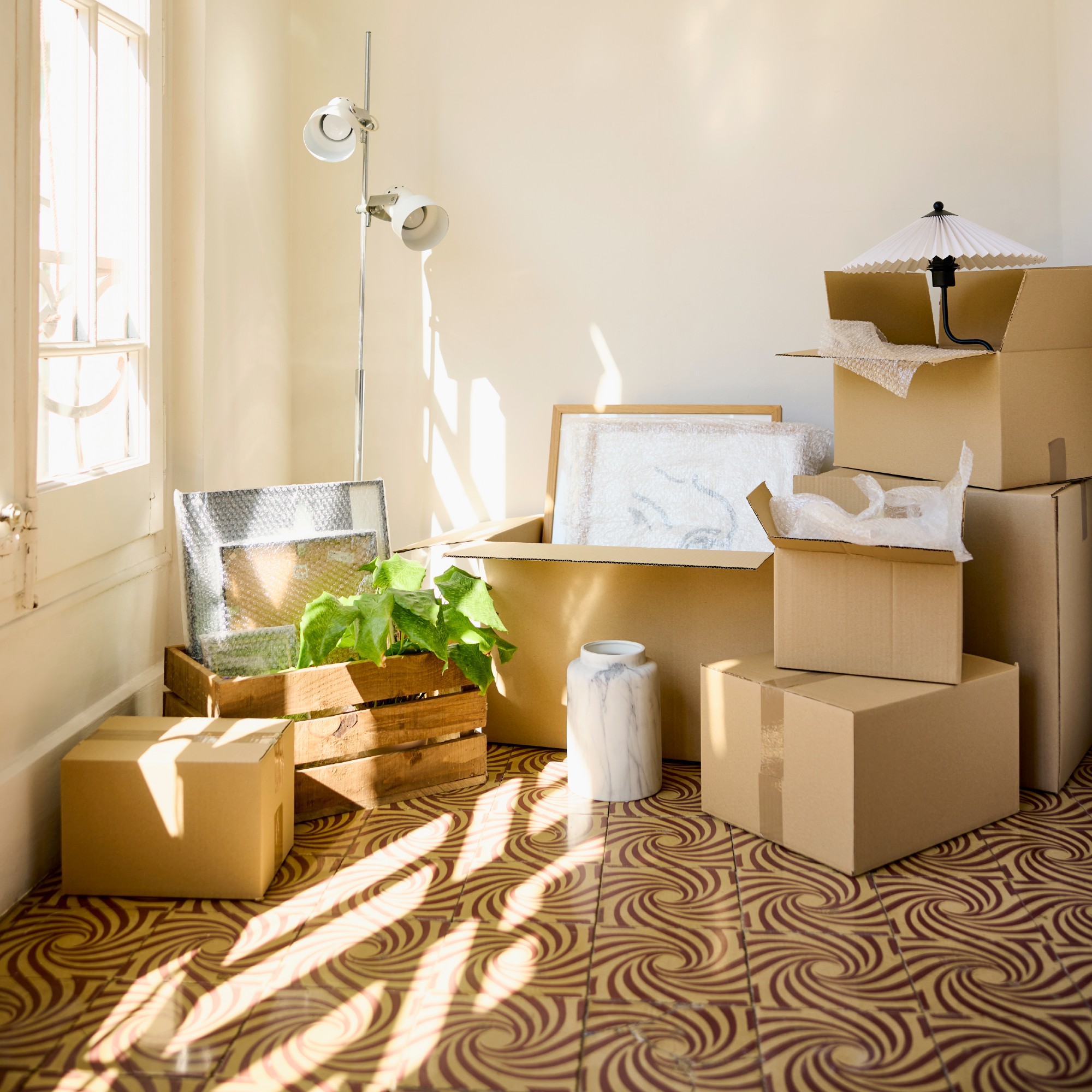 A room with opened cardboard boxes on a patterned tiled floor