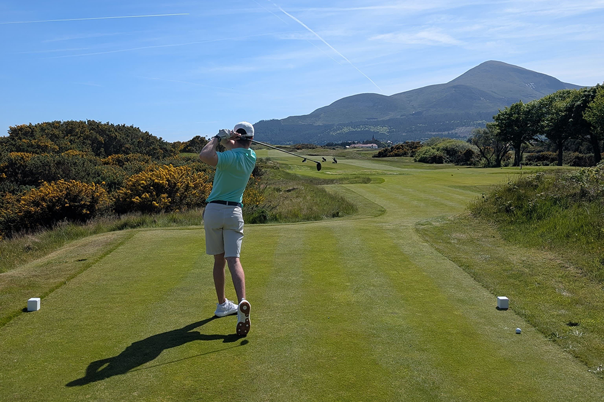 Conor Keenan hitting a 3-wood off the tee, in the finish position from behind