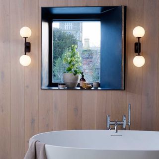 twin midecentury modern style lights in a bathroom above a freestanding bath
