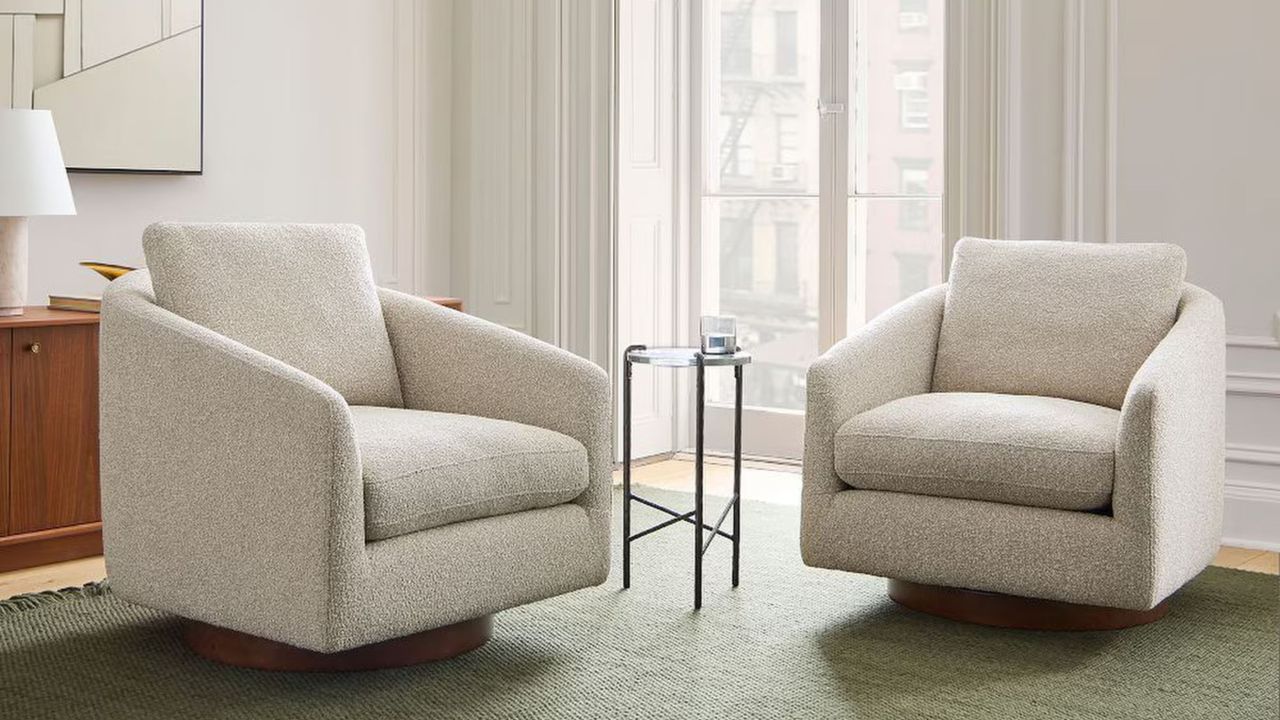 swivel armchairs in living room with small side table, timber console on the back wall with lamp and artwork on the wall, and green rug