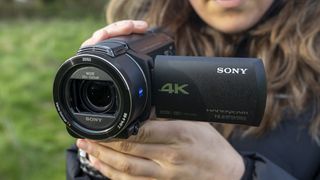 A front view of a photographer holding the Sony FDR-AX53 camcorder