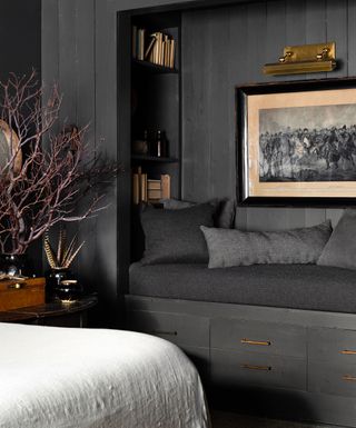 A grey-themed padded nook surrounded by wood panelling and above wooden drawers