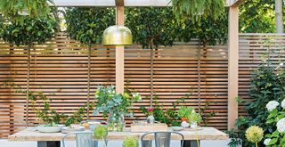 Small garden dining area with a slatted fence to allow the view to filter in to show how to make a small garden look bigger by creating a view