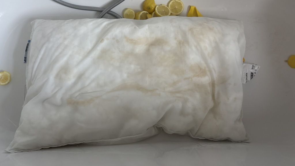 A pillow in a drained bathtub after being soaked in lemon water and baking soda.