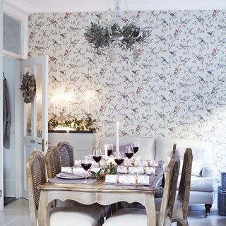 Dining room with bird wallpaper and table and chairs decorated for Christmas