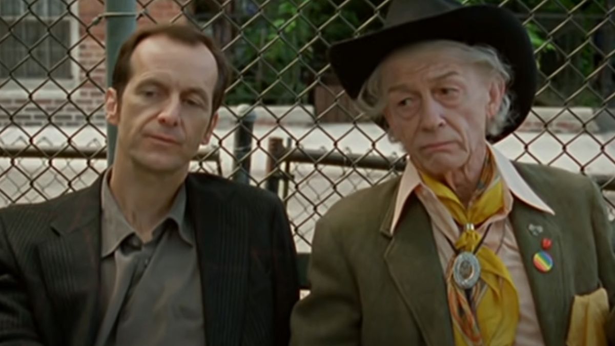 John Hurt in a cowboy hat sitting on a park bench with another man in An Englishman in New York