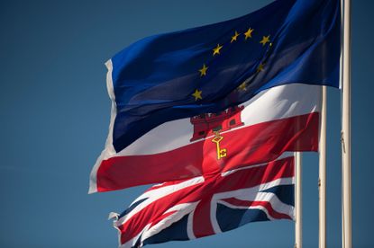 A Union Jack flag, Gibraltar's flag, and the EU flag