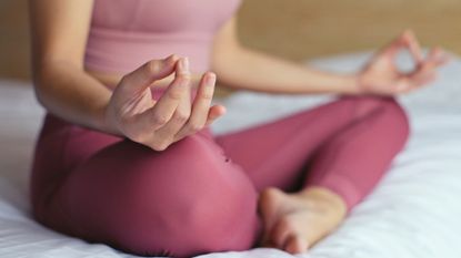 Bed yoga: An up close shot of a woman with crossed legs practicing yoga in bed